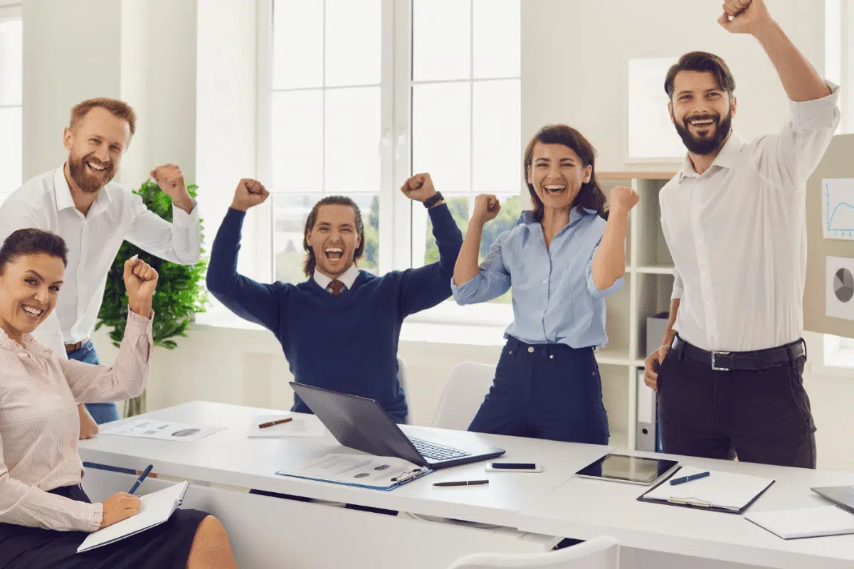 Trabalhadores felizes comemorando sucesso em reunião, após concluírem cursos online de desenvolvimento profissional